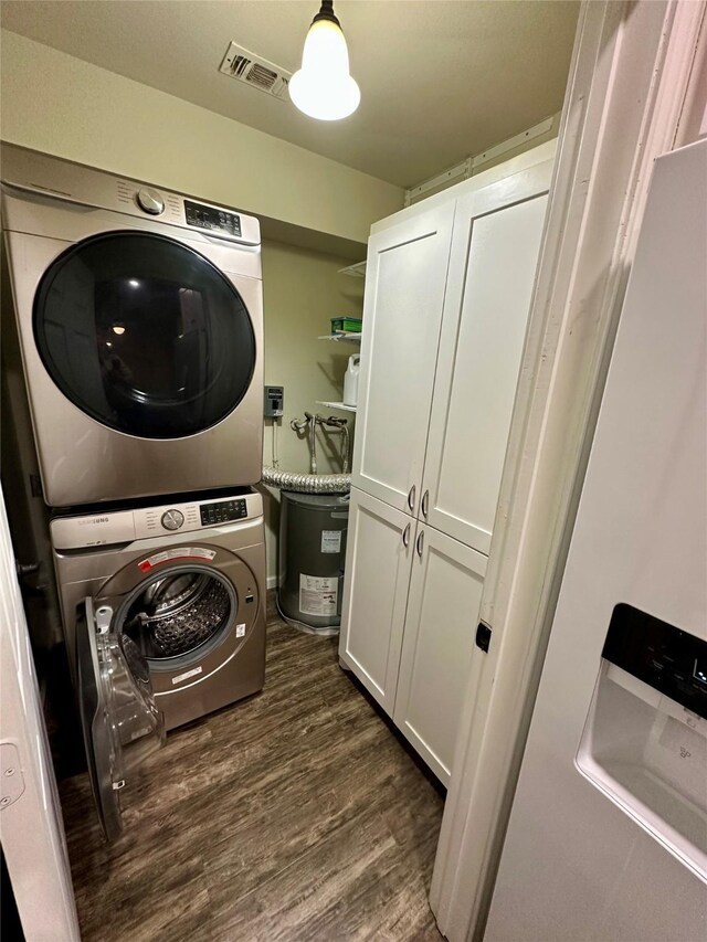 806 Mckinney Ave, Princeton, TX 75407 - clothes washing area featuring cabinet space, stacked washer and dryer, visible vents, and dark wood-type flooring