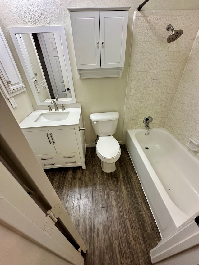 full bathroom featuring tiled shower / bath, vanity, wood-type flooring, and toilet