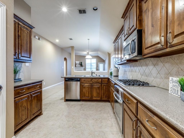 kitchen featuring sink, appliances with stainless steel finishes, tasteful backsplash, decorative light fixtures, and kitchen peninsula