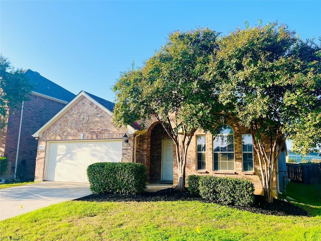 view of front of house featuring brick siding, concrete driveway, an attached garage, a front yard, and fence