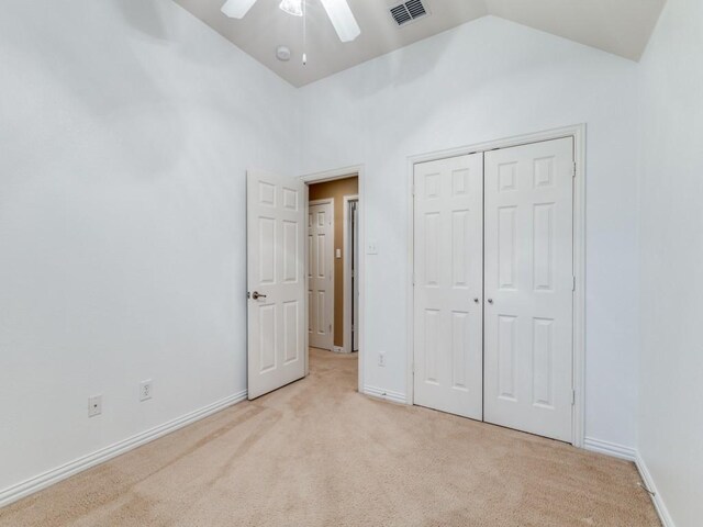 unfurnished bedroom with light carpet, a closet, vaulted ceiling, and ceiling fan