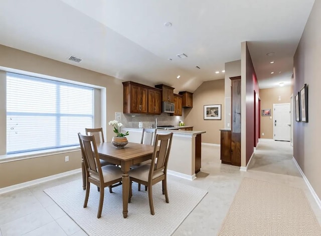 dining area featuring light tile patterned flooring and vaulted ceiling