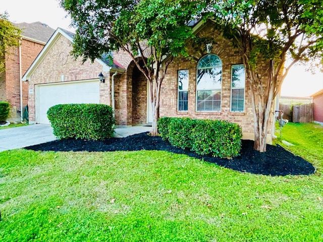 view of front of home featuring brick siding, fence, a garage, driveway, and a front lawn
