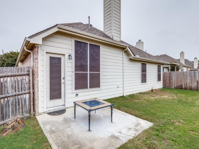 back of property featuring a patio, a yard, a fenced backyard, and a chimney