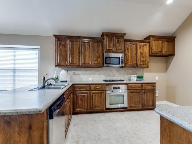 kitchen featuring kitchen peninsula, appliances with stainless steel finishes, backsplash, sink, and lofted ceiling