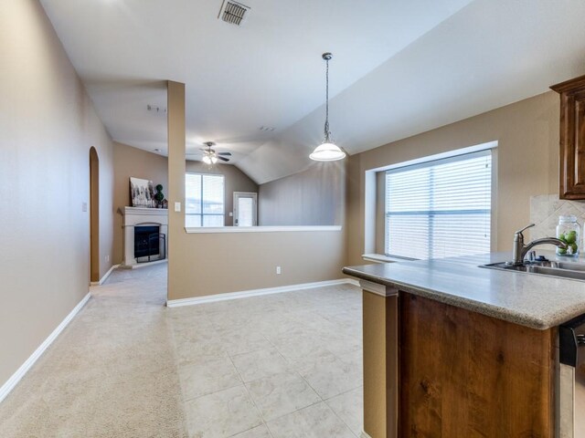 kitchen with lofted ceiling, sink, hanging light fixtures, decorative backsplash, and kitchen peninsula