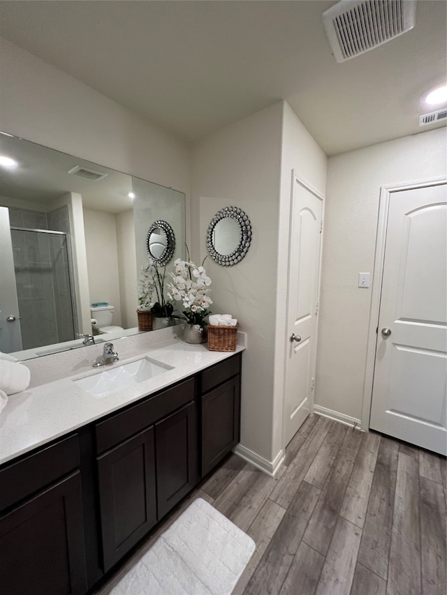 bathroom featuring toilet, an enclosed shower, vanity, and wood-type flooring