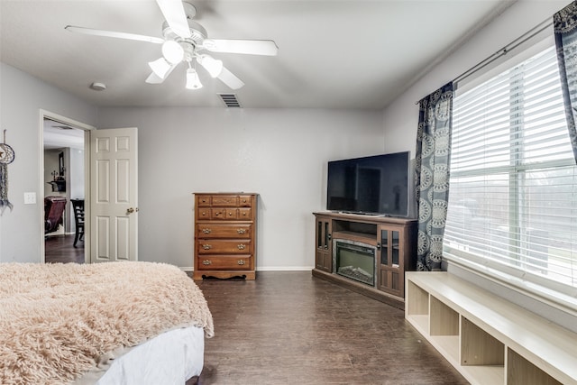 bedroom featuring dark hardwood / wood-style flooring, a fireplace, and ceiling fan