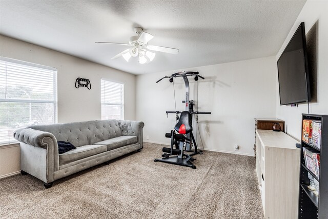 exercise room featuring light carpet, a textured ceiling, and ceiling fan