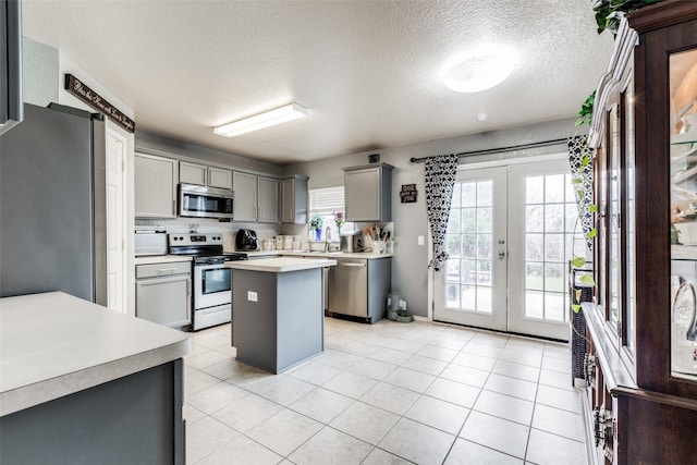 kitchen featuring french doors, a textured ceiling, a center island, stainless steel appliances, and gray cabinets