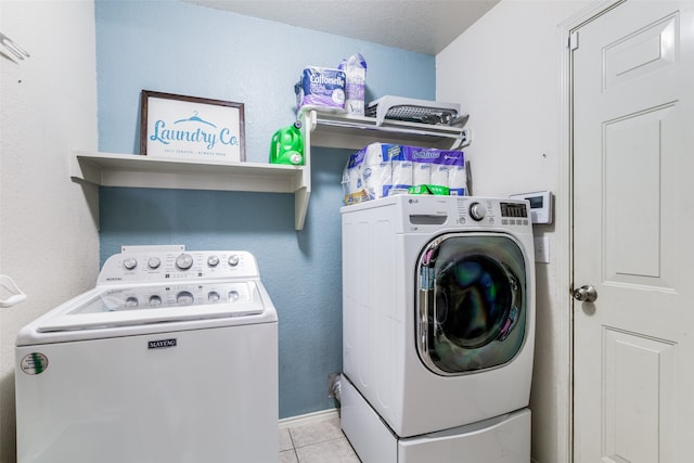 clothes washing area with independent washer and dryer, a textured ceiling, and light tile patterned floors