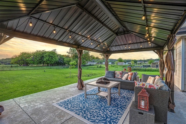 patio terrace at dusk with a gazebo, outdoor lounge area, and a lawn