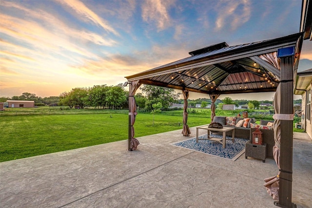 patio terrace at dusk featuring a gazebo, a lawn, and an outdoor living space with a fire pit