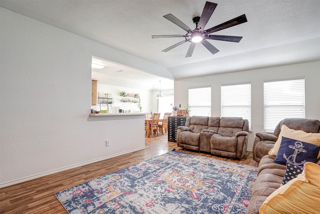 living room featuring ceiling fan with notable chandelier, hardwood / wood-style flooring, plenty of natural light, and lofted ceiling