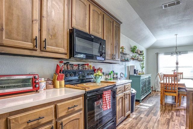 kitchen featuring pendant lighting, lofted ceiling, black appliances, a notable chandelier, and dark hardwood / wood-style flooring