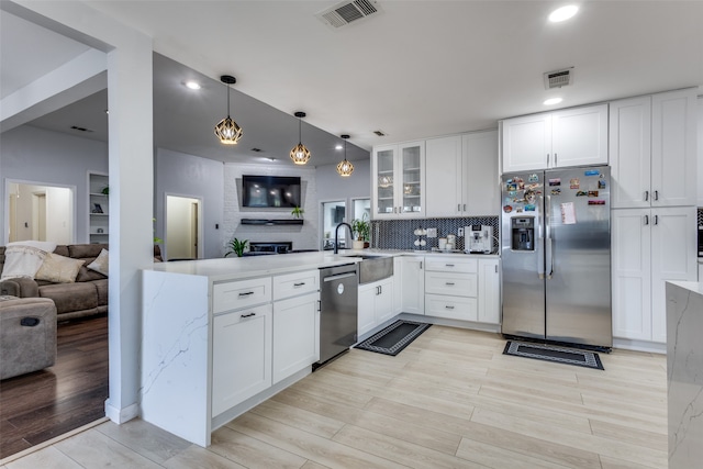 kitchen featuring white cabinetry, appliances with stainless steel finishes, decorative light fixtures, and decorative backsplash