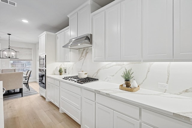 kitchen with light hardwood / wood-style floors, stainless steel gas cooktop, white cabinetry, decorative light fixtures, and decorative backsplash