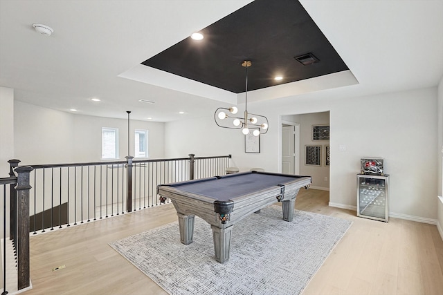 game room featuring a notable chandelier, light wood-type flooring, a raised ceiling, and pool table