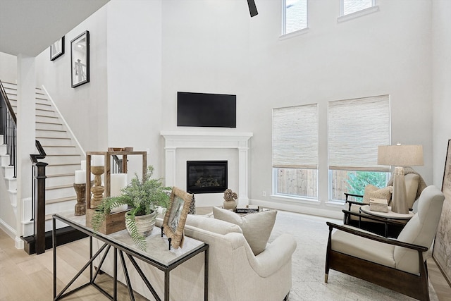 living room with a towering ceiling, a wealth of natural light, and light hardwood / wood-style floors