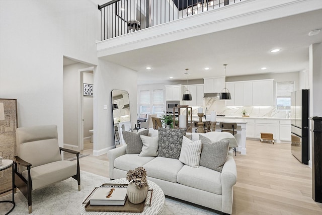 living room with a high ceiling and light hardwood / wood-style flooring