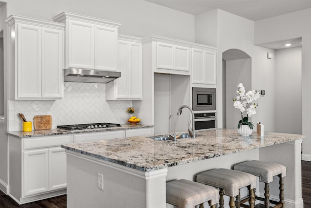 kitchen with appliances with stainless steel finishes, a sink, white cabinets, and under cabinet range hood