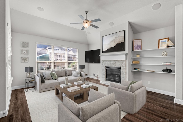 living area featuring a ceiling fan, a fireplace, baseboards, and dark wood-type flooring