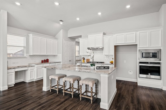 kitchen with white cabinetry, stainless steel appliances, a breakfast bar area, and a center island with sink