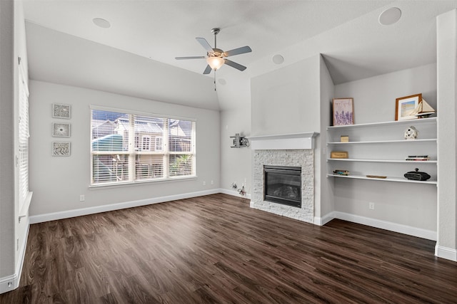 unfurnished living room with baseboards, a ceiling fan, lofted ceiling, dark wood-style flooring, and a stone fireplace