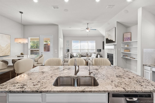 kitchen with lofted ceiling, sink, pendant lighting, a kitchen island with sink, and white cabinets