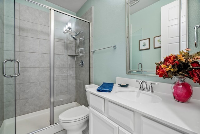 bathroom featuring vanity, a shower with shower door, and toilet