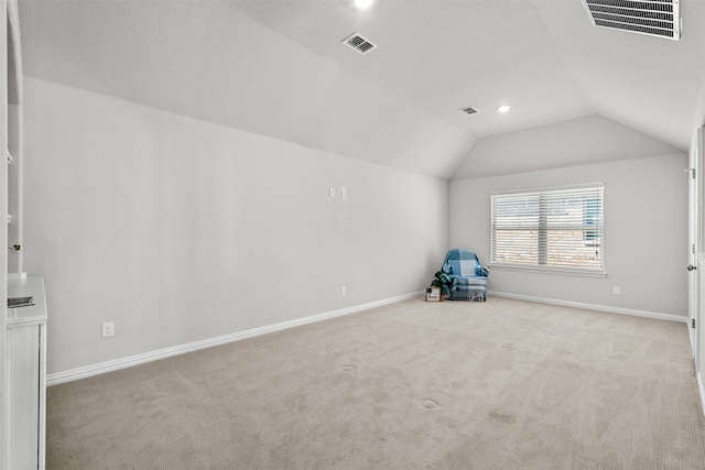 additional living space with baseboards, visible vents, vaulted ceiling, and light colored carpet