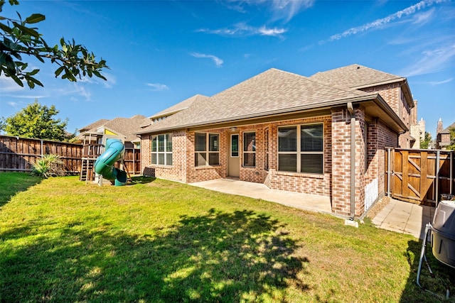 back of property featuring a playground, a fenced backyard, brick siding, a yard, and a patio area