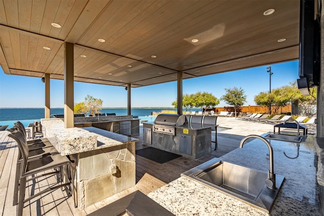 view of patio / terrace featuring a water view, grilling area, an outdoor kitchen, and an outdoor bar