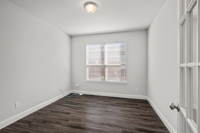 spare room featuring dark wood-style floors and baseboards