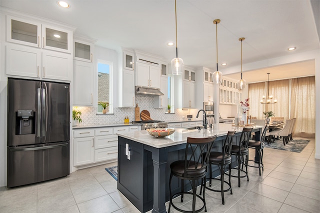 kitchen with white cabinets, hanging light fixtures, appliances with stainless steel finishes, a kitchen island with sink, and sink