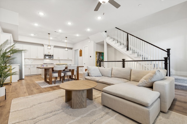 living room with ceiling fan and light hardwood / wood-style flooring