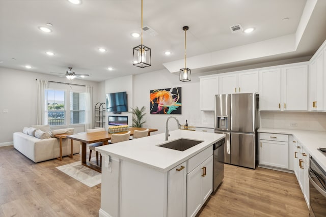 kitchen with ceiling fan, sink, appliances with stainless steel finishes, an island with sink, and white cabinets