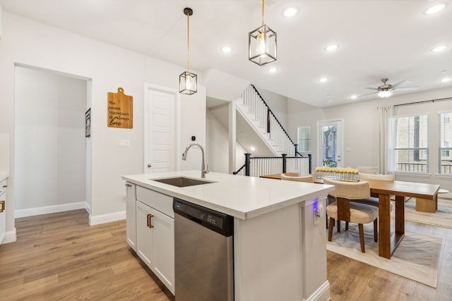 kitchen featuring white cabinetry, sink, hanging light fixtures, a kitchen island with sink, and stainless steel dishwasher