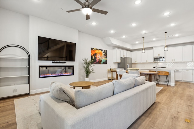 living room featuring ceiling fan and light hardwood / wood-style flooring