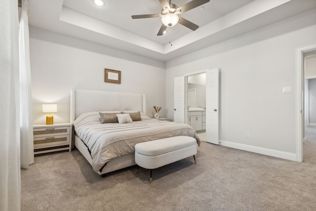 carpeted bedroom featuring ceiling fan, connected bathroom, and a raised ceiling