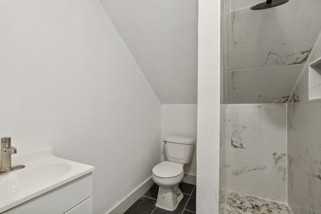 bathroom featuring vanity, a shower, vaulted ceiling, tile patterned flooring, and toilet