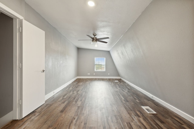 spare room with ceiling fan, dark wood-type flooring, and vaulted ceiling