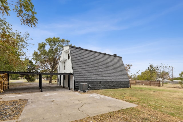 view of side of home with a yard, central AC, a carport, and a patio area