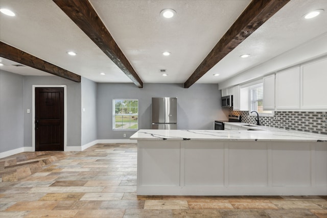 kitchen featuring sink, stainless steel appliances, beamed ceiling, kitchen peninsula, and white cabinets