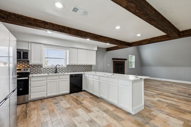 kitchen featuring kitchen peninsula, appliances with stainless steel finishes, white cabinets, and sink