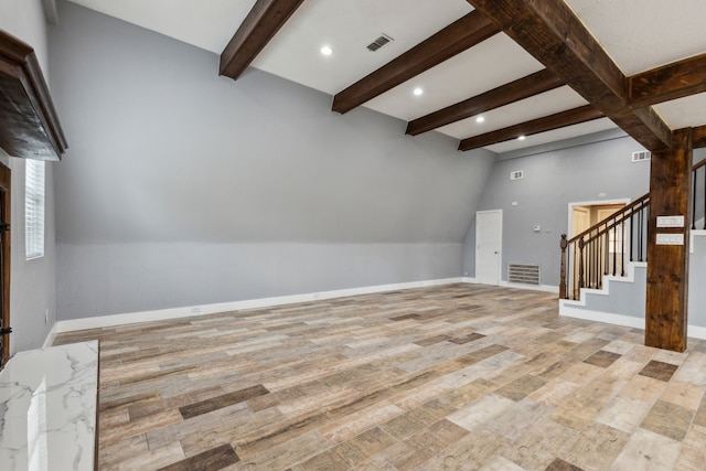 unfurnished living room featuring vaulted ceiling with beams and light wood-type flooring