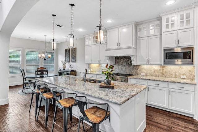 kitchen with a center island with sink, appliances with stainless steel finishes, white cabinets, and dark hardwood / wood-style flooring