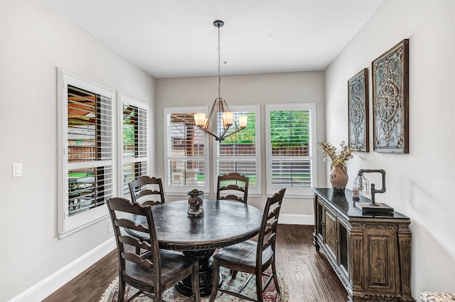 dining space featuring dark wood-type flooring and an inviting chandelier