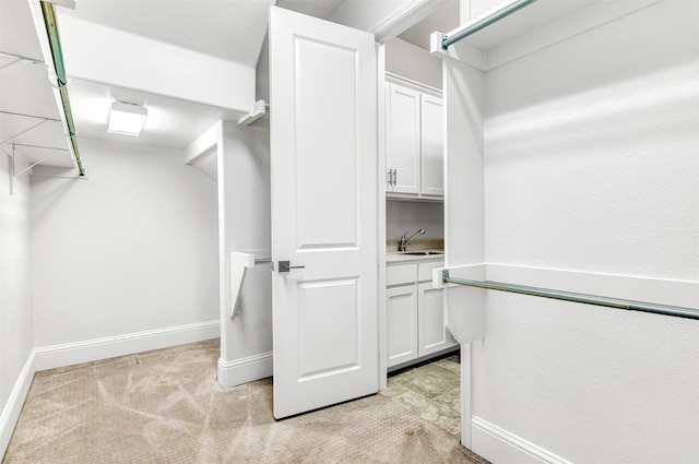 walk in closet with light carpet and sink