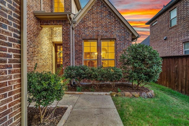 exterior entry at dusk featuring a lawn